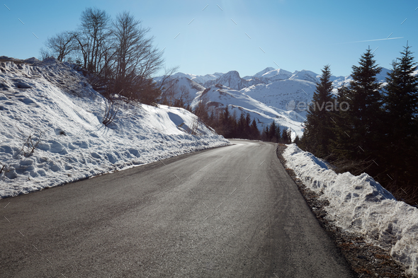 Empty mountain road descent on Alps, blue sky in a sunny day