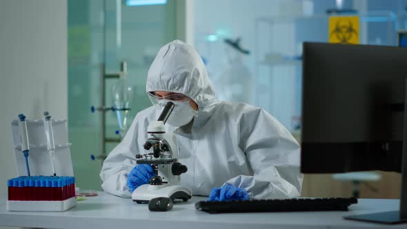 Biologist Doctor in Coverall Checking DNA Sample on Microscope alt