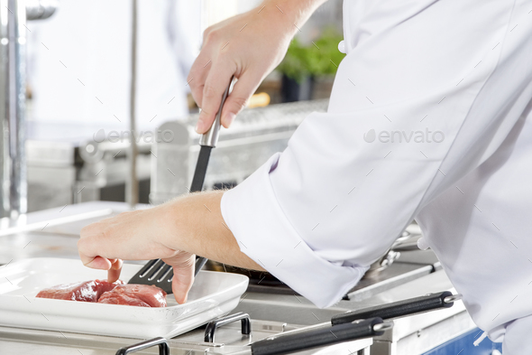 Close-up of a chef prepares beef steak in pan at the kitchen - Stock Photo - Images