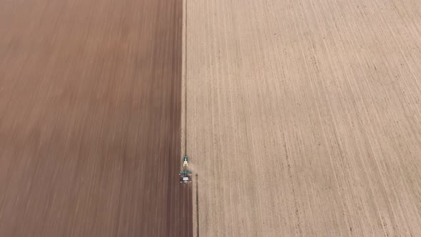 Aerial Shot of a Contrastive Agriculture Field with a Tractor Plowing It in Autumn