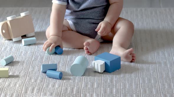 cute baby boy playing with eco wooden toys,train with carriages with cylinders and square form shape alt