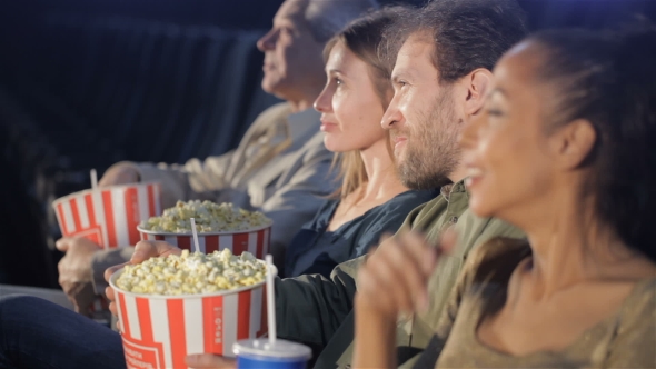 зритель в кинозале держит ведро с попкорном