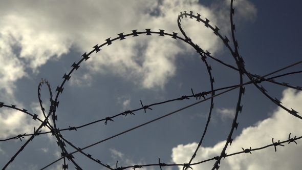 Barbed Wire Fence Against Blue Sky.