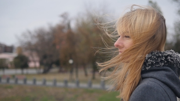 Young Girl Standing on the Street and Her Hair Fluttering in the Wind alt