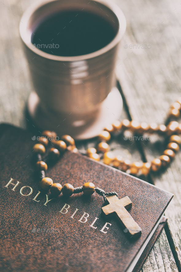 Rosary beads, holy bible and cup of wine.