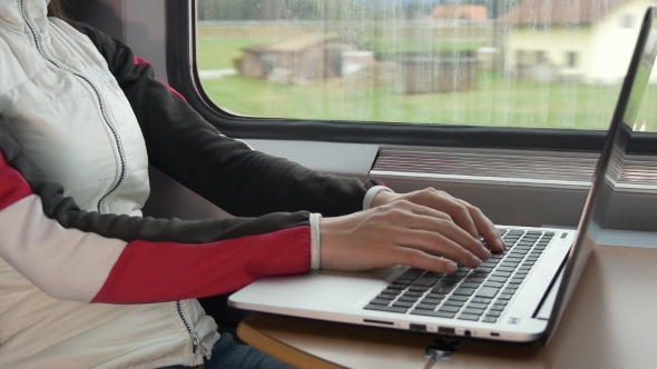 Hands on the Laptop Keyboard Near the Window in the Train