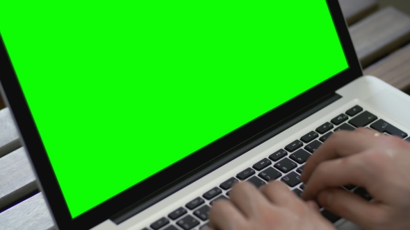 Hand of Man Working at Laptop Computer Typing on Keyboard. Green Screen