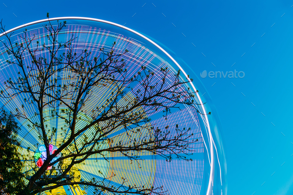 Tree Branches Against Backdrop Of Bright Spinning Ferris Wheel A - Stock Photo - Images