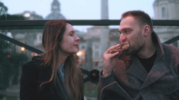 Young Attractive Couple Have a Break in City Centre. Man and Woman Sitting in the Evening Outdoors alt