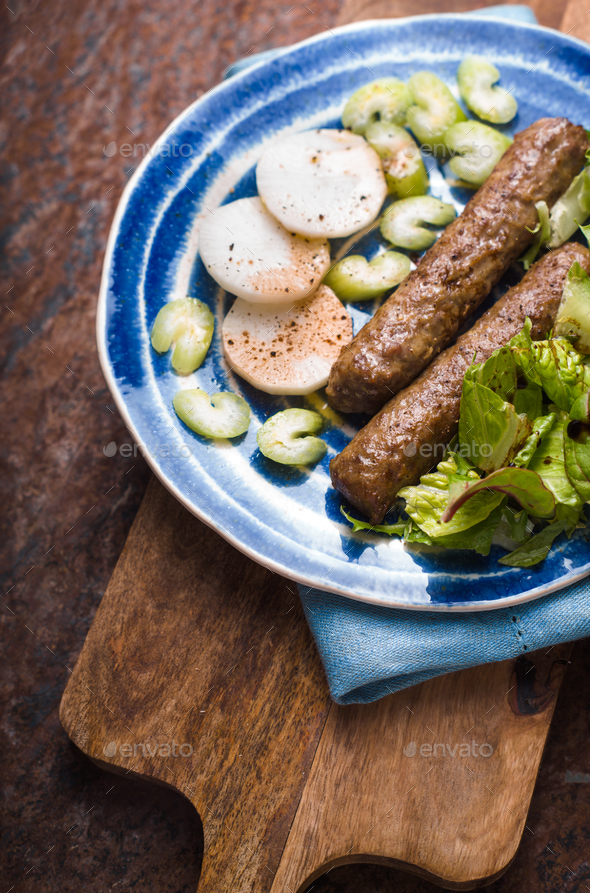 Chevanchichi with lettuce and daikon on a blue plate on the board - Stock Photo - Images
