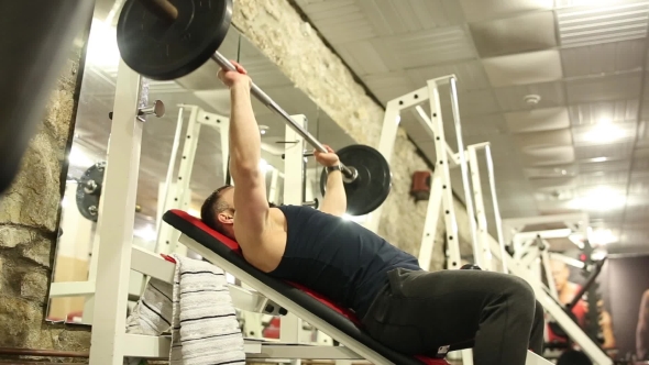 Young Man with a Beard in Black T Shirt Is Training in the Gym alt