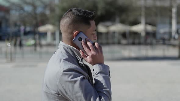 Cheerful Middle Eastern Man Talking on Smartphone Outdoor alt