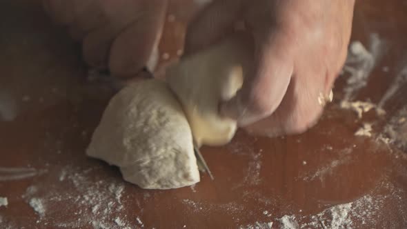 Women's Hands Cut the Freshly Cooked Dough with a Knife