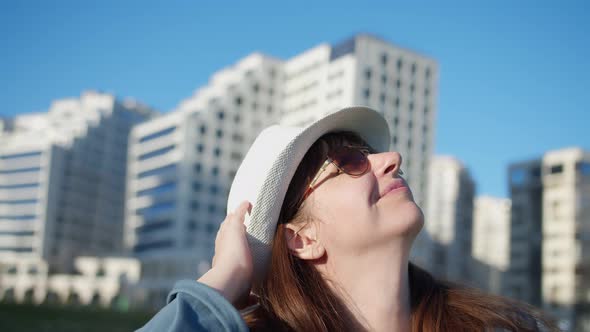 Profile of a Happy Woman in a Hat on the Street Looking at the Sky and Smiling Travel Concept