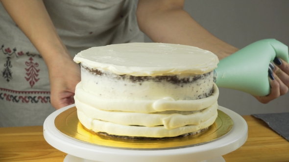 Confectioner Decorates the Cake and Cover It with Butter Cream. Confectionery Tools: Spatula for alt