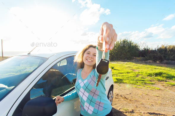 auto business, car sale, consumerism and people concept - happy woman holding new car key outdoor