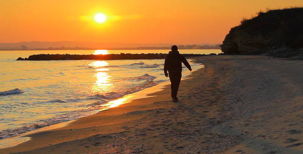 Man Walks On The Beach At Sunset