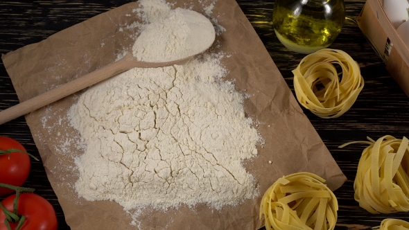 Pasta, Eggs, Oil, Tomatos, Garlic and Flour on Wooden Background