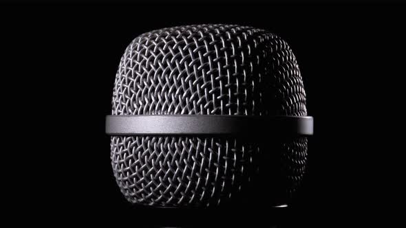 The Microphone Rotates on a Black Background. Dynamic Microphone Grid Spins Close-up alt