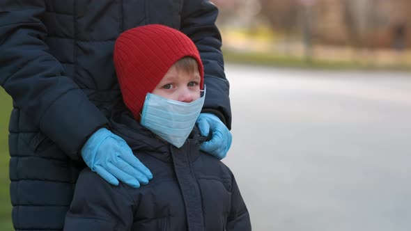 Mom with a small son stands on the street of a European city in a medical mask