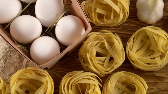 Pasta, Eggs, Oil, Tomatos, Garlic and Flour on Wooden Background