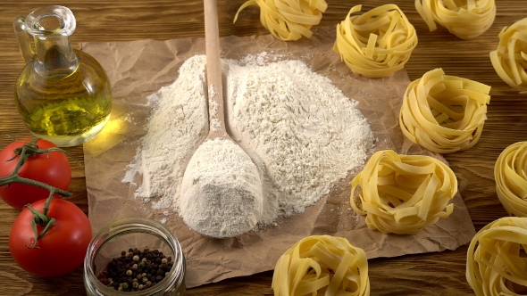 Pasta, Eggs, Oil, Tomatos and Flour on Wooden Background