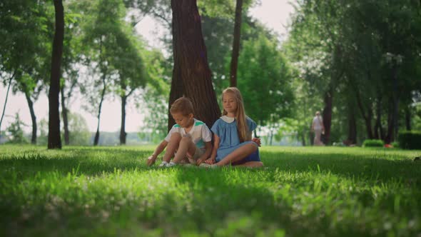 Laughing Kids Sitting Under Tree in Green Park alt