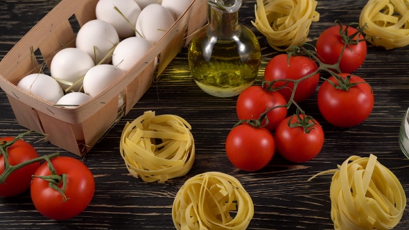 Pasta, Eggs, Oil, Tomatos and Garlic on Wooden Background