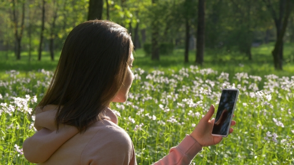 Woman Browses Internet in Phone Among Flowers