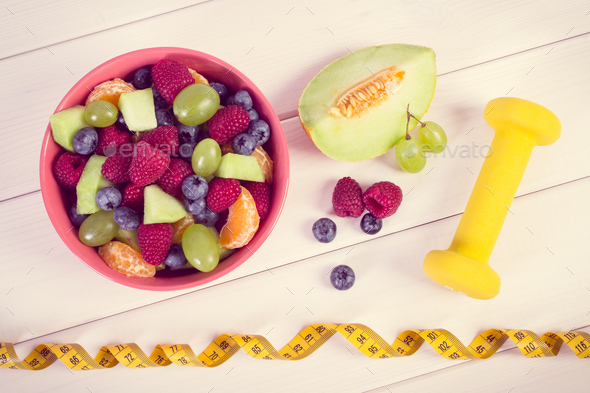Vintage photo, Fresh fruit salad and centimeter with dumbbells - Stock Photo - Images