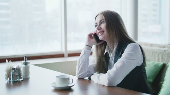 One Business Woman Is Sitting in a Cafe and Smiling and Talking on the Phone