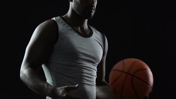 Tall Black Athlete Carrying Basket Ball in Hands, Thinking About Game Strategy alt