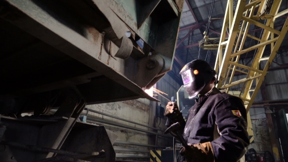 The Welder Puts on the Mask and Starts To Weld the Metal Parts of the Broken Railway Car.