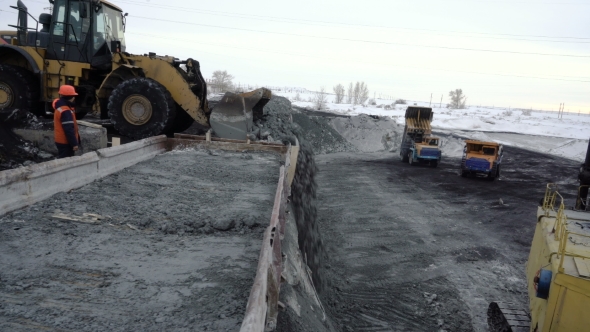 Bulldozer Unloading Freight Train with Copper Ore at the Platform