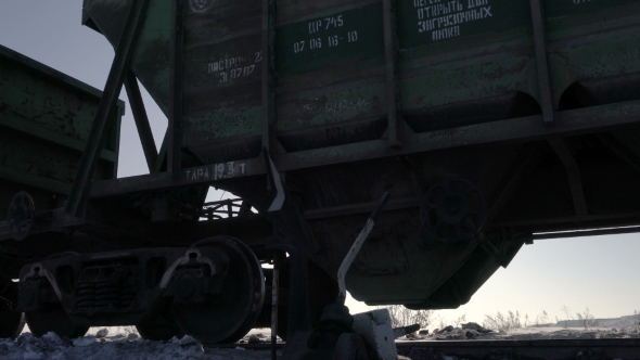 Low Angle View of Freight Cars Moving By Rail Near the Railroad Switch Against the Sun in Winter