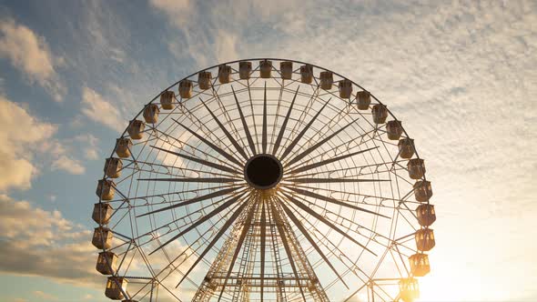 Ferris wheel silhouette at sunset - time lapse - against beautiful clouds in the sky alt