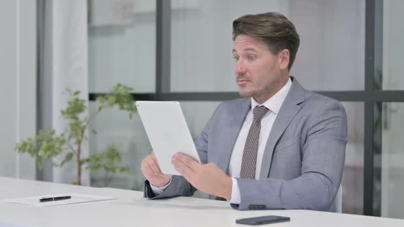 Middle Aged Man Celebrating Success on Tablet in Office alt