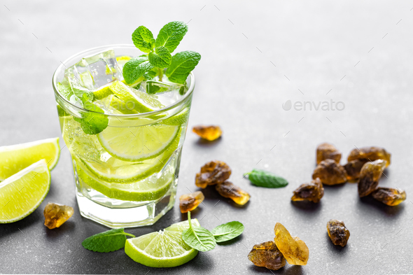 Summer mint lime refreshing cocktail mojito with rum and ice in glass on black background - Stock Photo - Images