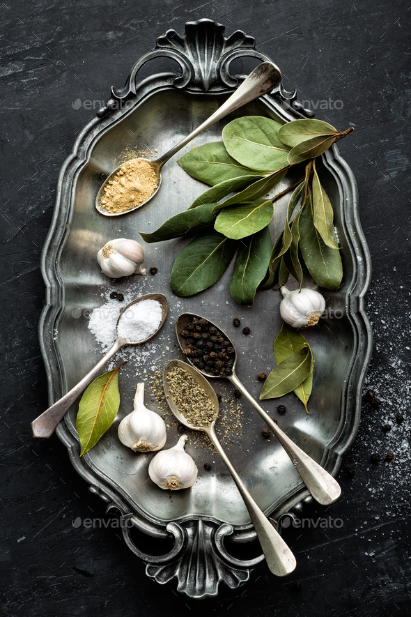 Dark culinary background with bay leaves, salt, pepper and garlic - Stock Photo - Images