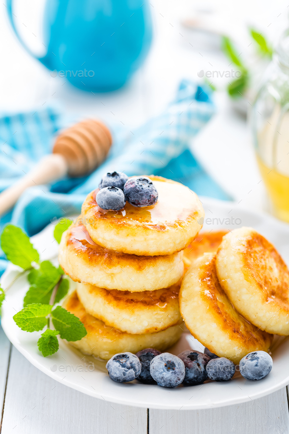 Cottage cheese pancakes with honey and blueberry on white background, breakfast or lunch - Stock Photo - Images