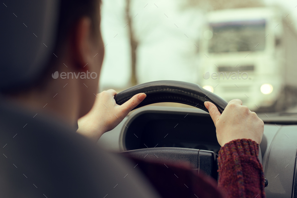 Woman driving car toward a large truck on the road - Stock Photo - Images