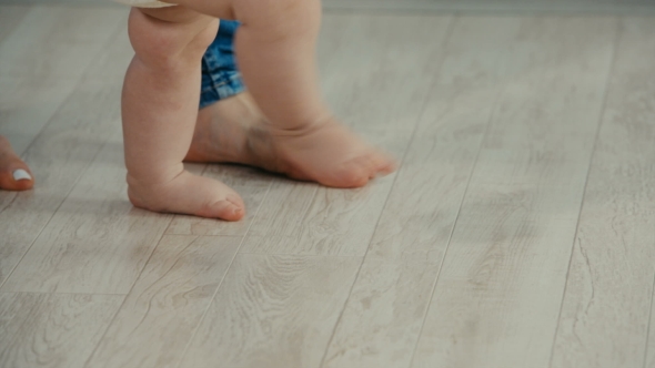 Legs of Mother and Baby. Baby Daughter Take First Steps alt
