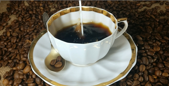 Pouring milk into the cup of fresh brewed coffee in slow motion