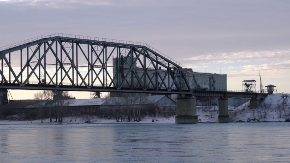 Tracking PAN of Railway Bridge Over the River at Dawn with Industrial Building in the Background.