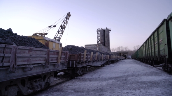 PAN of Sets of Gandola Cars with Copper Ore in Winter. Excavator Boom in the Background.