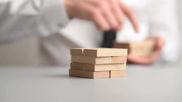 Businessman Stacking Wooden Pegs