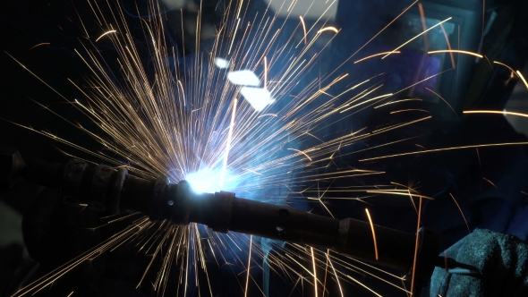 Welder Builds Up the Metal on the Workpiece. Sparks From Welding. Welding Mask