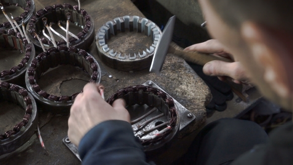 Mechanic Repairing Electric Motor Stator. Aligns with a Hammer.