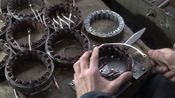 Mechanic Repairing Electric Motor Stator. Aligns with a Hammer.