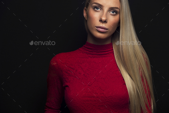 Dark portrait of a blonde woman in red dress - Stock Photo - Images